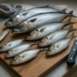 木製まな板の上に並べられた新鮮な釣り魚と包丁・ウロコ取り