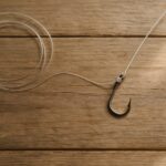 木製テーブルの上に置かれた釣り針とナイロンラインのクローズアップ俯瞰写真