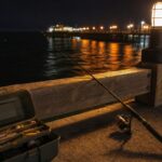 夜の堤防で常夜灯の光が水面に映り込む夜釣りのシーン