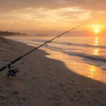 朝焼けの砂浜に立てかけられたサーフフィッシング用ロッドと静かな海