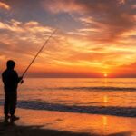 夕暮れのサーフでロッドを構えるアングラーのシルエット