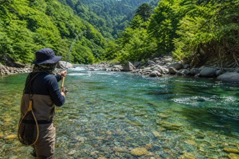 夏の清流で鮎の友釣りを楽しむシーン。竿が弧を描き、透明な川が輝いている